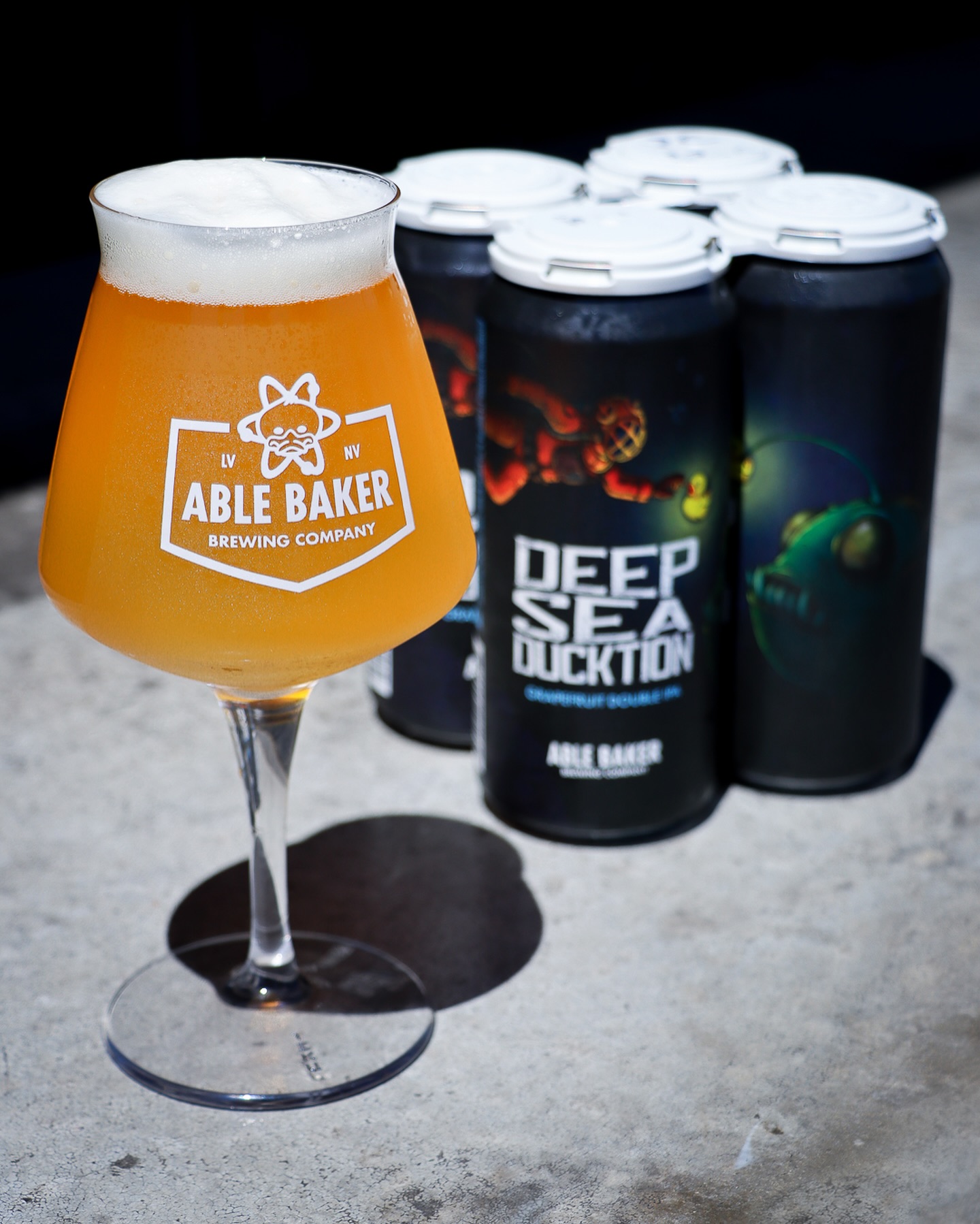 glass of able brewing beer and multiple beer cans 