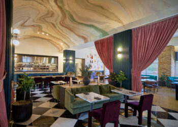 Image of the elegant interior of Zio's Italian Steakhouse in Las Vegas. The main dining area has hints of sage green, brick red, and tan colors