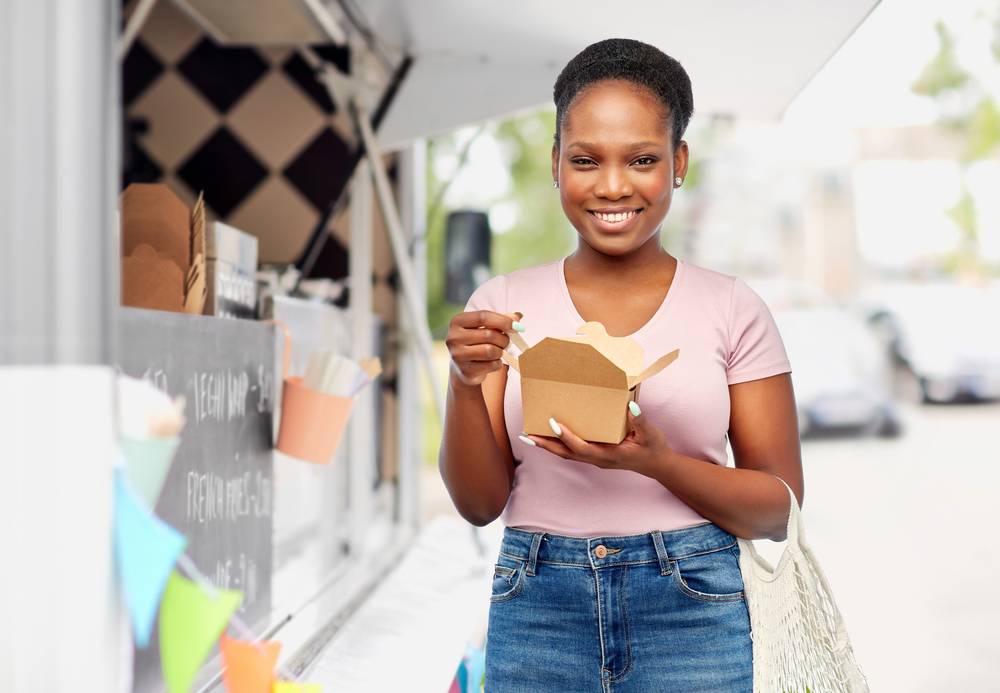 happy woman eating food next to a food truck 